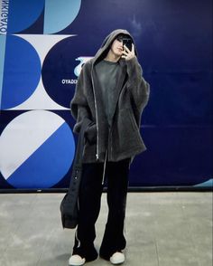 a woman standing in front of a blue wall talking on her cell phone while wearing black sweatpants