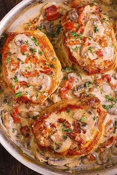 a pan filled with mushrooms, tomatoes and cheese on top of a wooden table next to bread