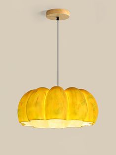 a yellow light hanging from a ceiling with five bananas on the bottom and one banana below it