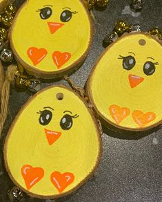 three wooden slices with painted faces and hearts on them are hanging from twine strings