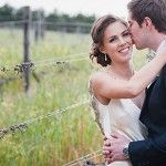 a bride and groom kissing in front of a barbed wire fence