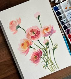 a watercolor painting of pink flowers on white paper with paintbrushes next to it