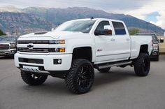 a large white truck parked in a parking lot with mountains in the backgroud