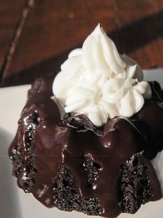 a piece of chocolate cake with whipped cream on top is sitting on a white plate