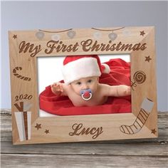 a wooden frame with a baby's first christmas photo in the center and santa hat on top