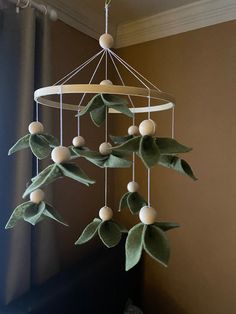 a wind chime with green leaves and white balls hanging from it's sides