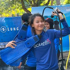 two women in blue shirts are holding up scuba equipment