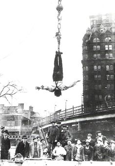 an old black and white photo of people hanging upside down in the air from a crane