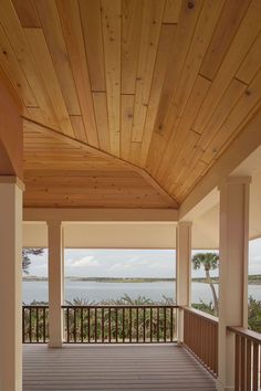 an empty porch with wooden flooring overlooking the water