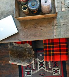 a wooden table with a laptop and other items on it next to a red rug