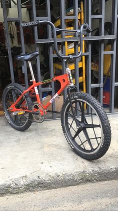 a red bicycle parked in front of a metal gate with bars on it's sides