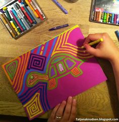 a person is drawing on a piece of paper with crayons and colored pencils