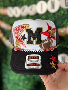 someone is holding up a hat with the letter m on it and stars around it