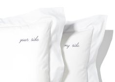 two pillows with embroidered words on them sitting side by side, one is white and the other has black lettering