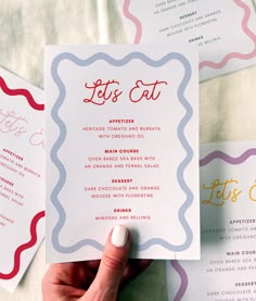 a person holding up a menu card in front of some other cards on the table