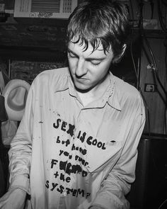 black and white photograph of a young man wearing a shirt with writing on it