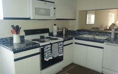 a kitchen with white cabinets and blue counter tops is pictured in this image, there are two tea towels hanging on the stove