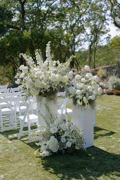 an outdoor ceremony setup with white flowers and greenery