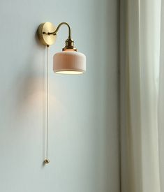 a wall light that is on the side of a white wall next to a window