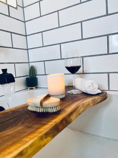 a bath tub with a wooden counter top next to a glass of wine and a brush