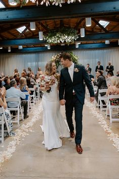 a bride and groom walking down the aisle after their wedding ceremony in an indoor venue