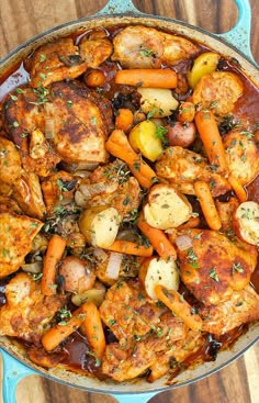 chicken stew with carrots and potatoes in a blue skillet on a wooden table