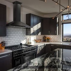 a large kitchen with black cabinets and marble counter tops, along with an island in the middle