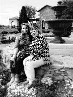 two women are sitting on a stone bench