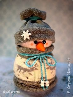 a small snowman wearing a knitted hat and scarf with a carrot in it's mouth