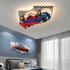 a bedroom with blue walls and a race car suspended from the ceiling above the bed