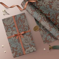 a gift wrapped in brown and blue paper with a ribbon on it next to a penny