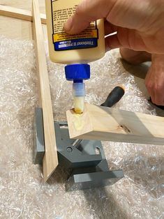 a person is using glue to make a piece of wood