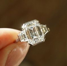 a close up of a person's hand holding an old - fashioned diamond ring