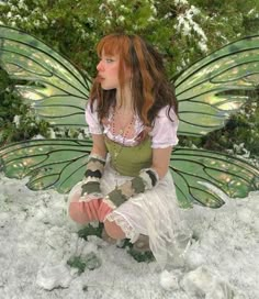 a woman dressed as a fairy sitting in the snow