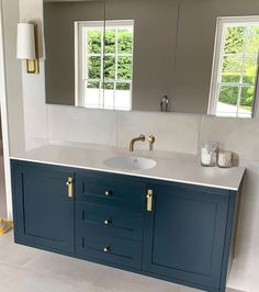 a bathroom with blue cabinets and mirrors on the wall, along with a white tiled floor