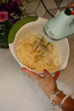 a woman is mixing rice in a bowl with an electric hand mixer on the counter