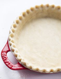 an uncooked pie crust in a red dish on a white counter top with the word bake written below it