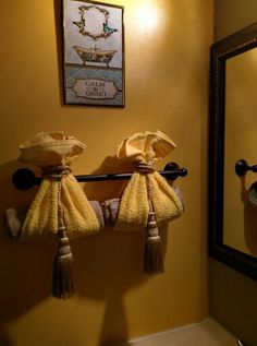 two towels are hanging on the towel rack in front of a mirror and light fixture