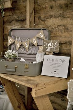 an open suitcase sitting on top of a wooden table next to a card and gifts sign