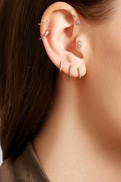 a woman wearing an ear piercing with three stones on the top and bottom of her ear