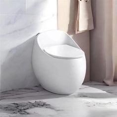 a white toilet sitting on top of a bathroom floor next to a shower curtain and window