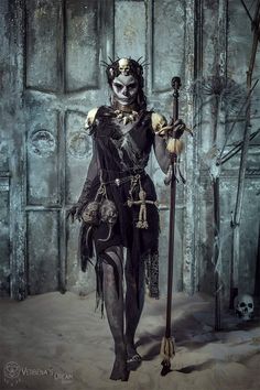 a woman dressed up as a demon holding a broom and wearing a costume with skulls on it