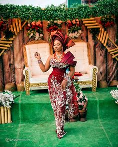 a woman in a red and white dress standing on a green carpeted area with flowers