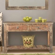 a wooden table with two drawers and a bowl of fruit on it next to a mirror