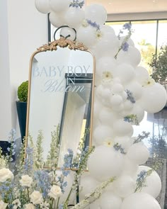 balloons and flowers are on display in front of a mirror at a baby boy shower