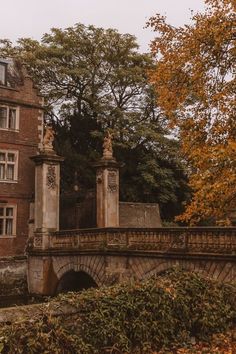 an old brick building with a stone bridge in front of it and lots of trees