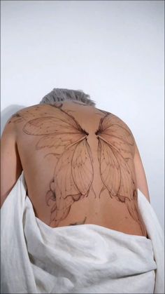 the back of a woman's shoulder with a butterfly tattoo on it