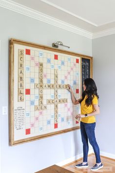 a woman standing in front of a large scrabble board