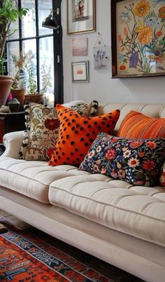 a living room filled with lots of different types of pillows on top of a couch