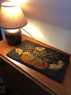 a lamp is sitting on a table next to a rug with an image of flowers